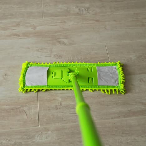 cleaning the house. green microfiber mop moving on the parquet floor to keep the house clean. housekeeping concept. close-up.