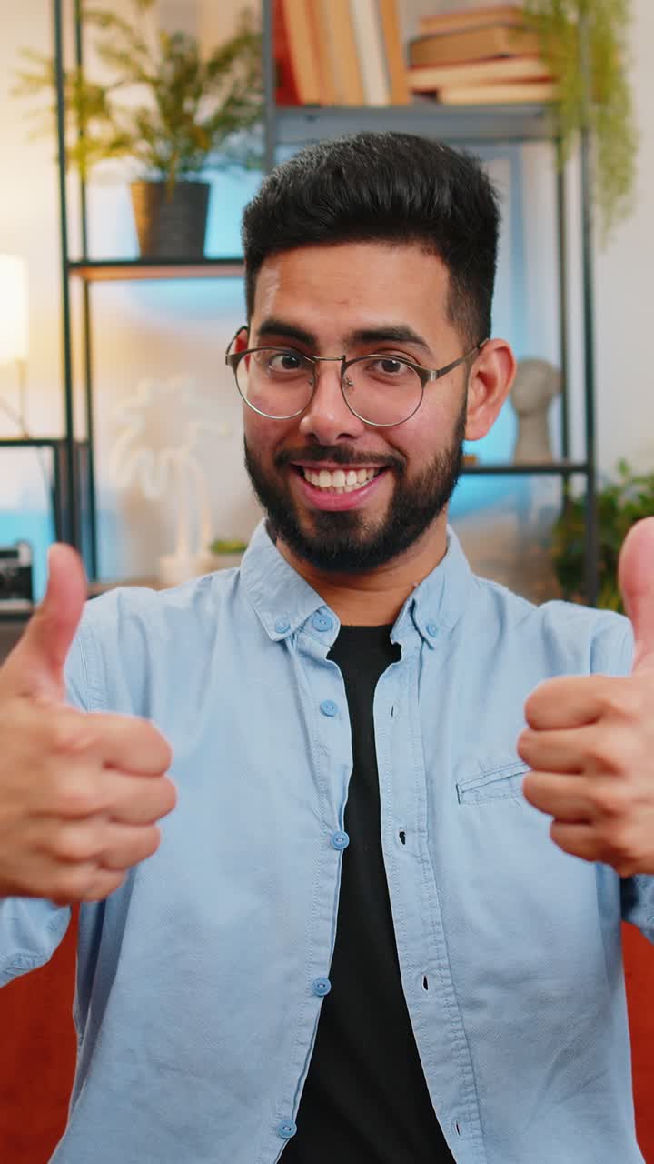 Indian young man celebrating success approvingly showing thumbs up like sign positive good feedback