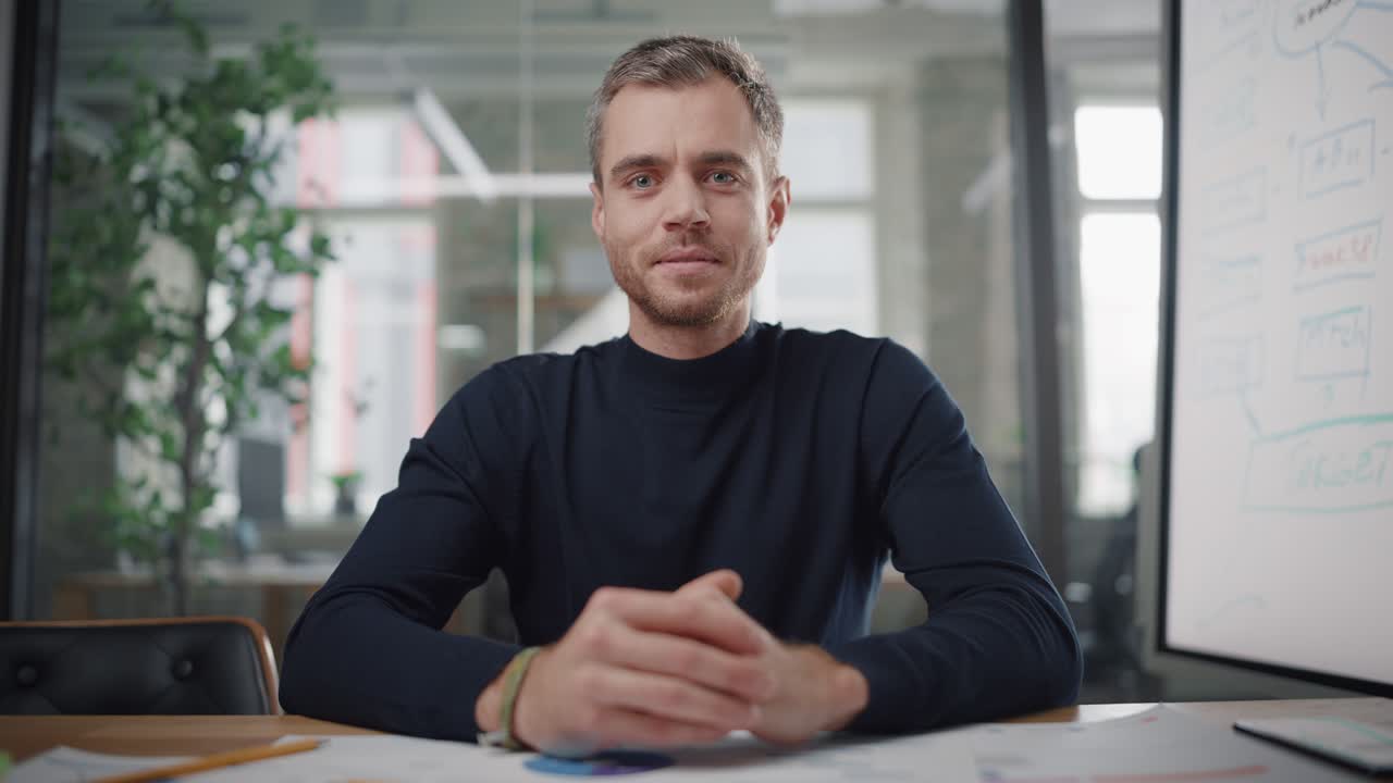 Punto di vista dalla telecamera con un giovane e affascinante project manager che effettua una videochiamata in un ambiente d'ufficio creativo. Felice specialista maschio caucasico che parla con un collega tramite una telecamera in diretta.