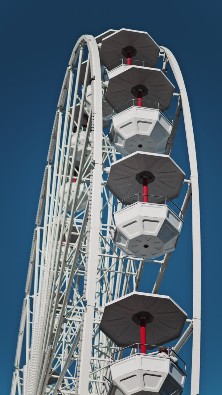 Close up of people in a cabin in a Ferris Wheel with the blue sky on the background. Vertical