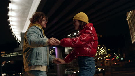 lovely couple dancing under bridge. man and woman holding hands on urban street.