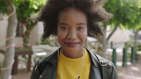 retrato de una estudiante afroamericana de moda con un afro funky sonriendo alegremente mirando a la cámara disfrutando escuchando música usando auriculares