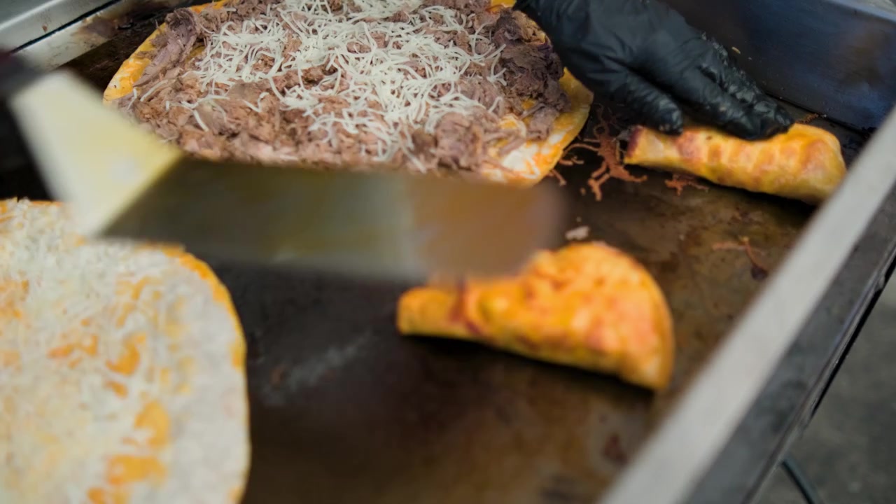 Filmagem de comida mexicana mostrando a dobragem de um taco quesabirria durante a preparação e o serviço de autênticos tacos quesabirria.