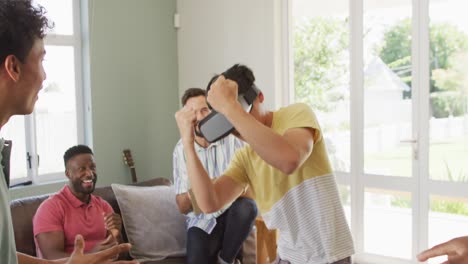 Fröhliche,-Vielfältige-Männliche-Freunde,-Die-Im-Wohnzimmer-Reden-Und-Ein-VR-Headset-Verwenden