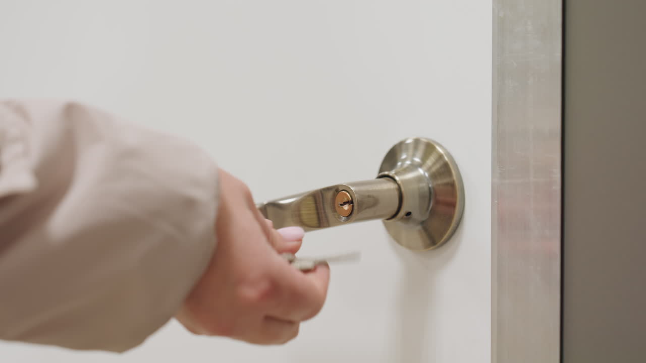 Close up detail of door as person locks from inside using key and pulls handle to ensure closure, emphasizing routine security, metallic design, and smooth closure in bright indoor environment
