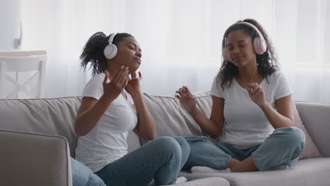 two girls listening to music and dancing on a couch