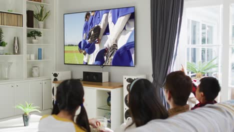 Composite-of-happy-family-sitting-at-home-together-watching-baseball-game-on-tv