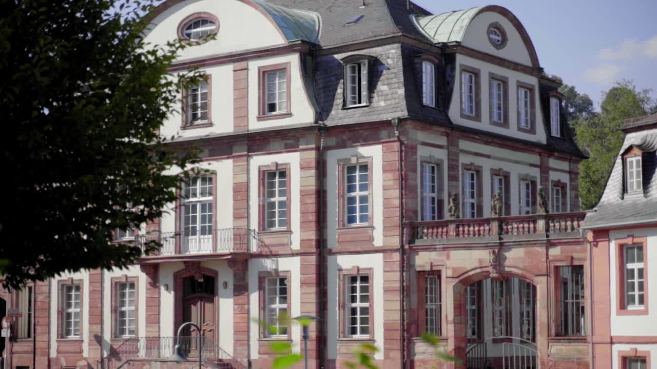 Slow-motion shot of the traditional building of Von der Leyen High School in Blieskastel. A summer day with bright light highlights the elegant architectural details and surrounding greenery.