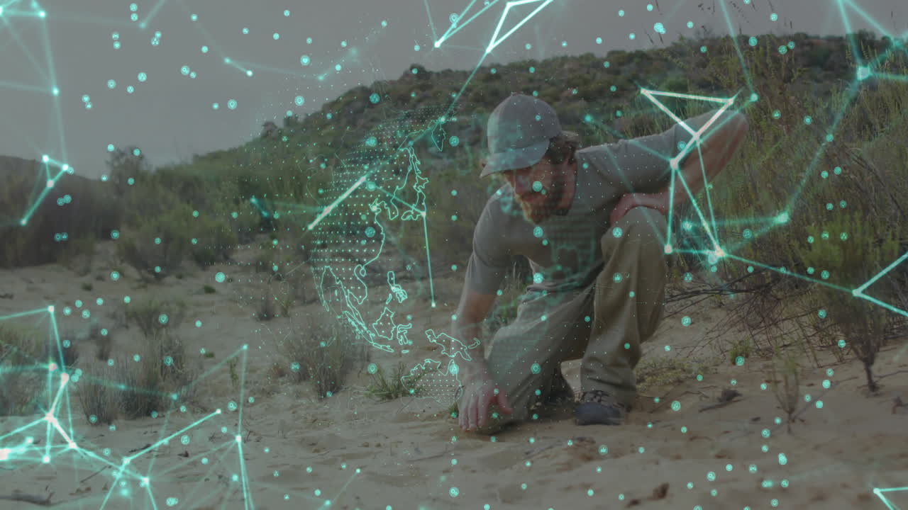 Field researcher kneeling on desert scrub studying soil, showing glowing technology network data