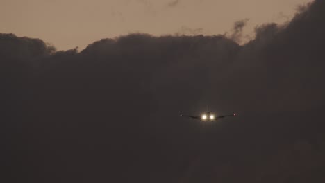 plane with headlights ascending against heavy clouds in evening sky