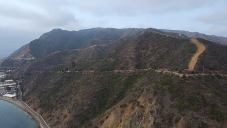 vista aérea al sendero de las colinas, cresta, cielo nublado y parque industrial avalon, catalina