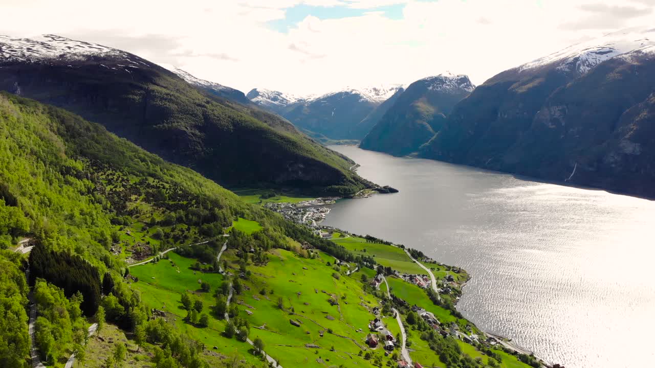 aérea: volando sobre el fiordo sognefjord desde la ladera de una montaña y una ciudad al fondo
