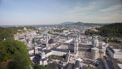 a wide-open city view of salzburg in austria in the morning with lots of buildings and a blue sky with white clouds in the background