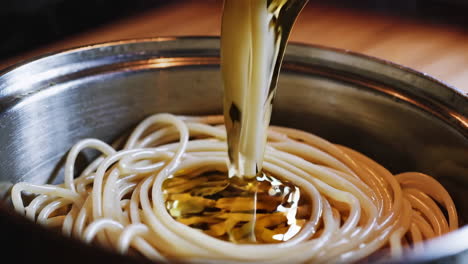 pouring olive oil on spaghetti