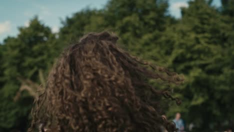 Camera-tracking-smiling-young-caucasian-woman-with-curly-hair-dancing-at-music-festival.