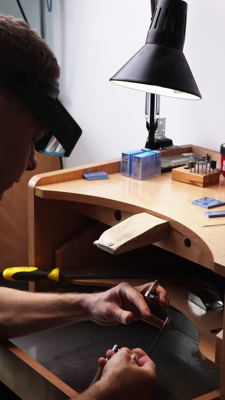 Jeweler Cutting Metal with a Saw at a Workshop Bench