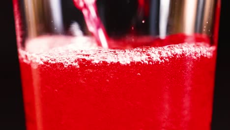 red fizzy drink poured into a tall glass