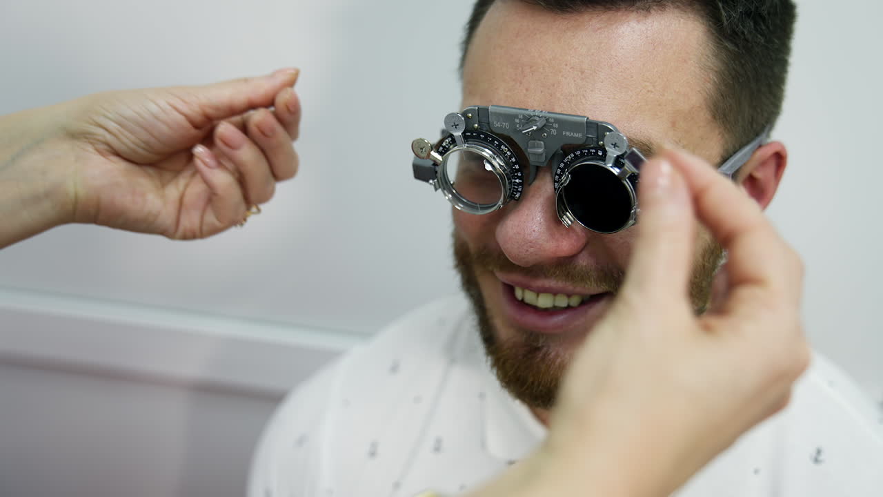 Smiling happy male patient in corrective testing glasses. Checking up eyesight in clinic. Handsome patient in ophthalmology.