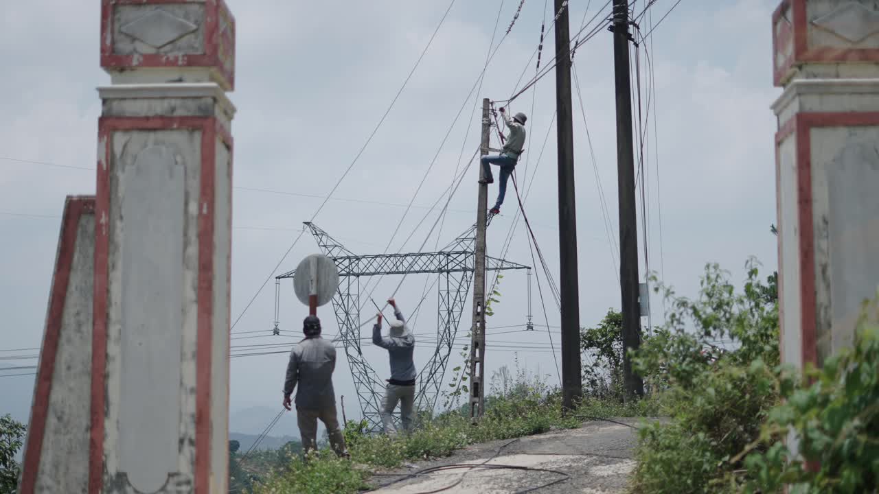 Workers repairing power lines on a rural hillside