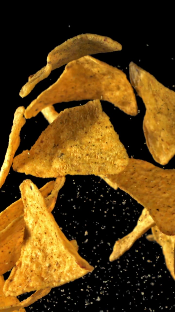 Tortilla chips che cadono con condimento su sfondo nero al rallentatore