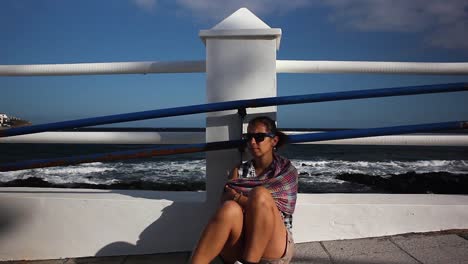 Wide-shot-of-a-young-girl-sitting-on-the-ground-by-the-sea