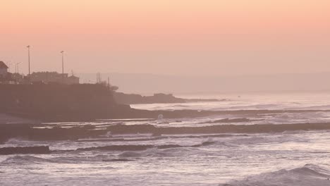 Amplia-Vista-De-Las-Olas-Golpeando-La-Costa-De-Lisboa-Al-Amanecer