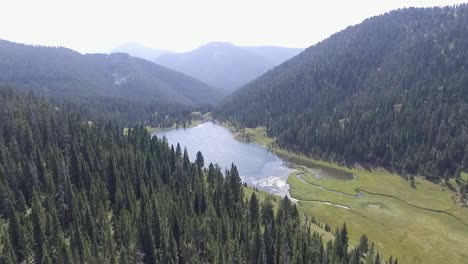 Die-Drohne-Schleicht-Sich-Näher-An-Den-Blauen-See-Heran,-Der-Von-Bergen-Umgeben-Ist