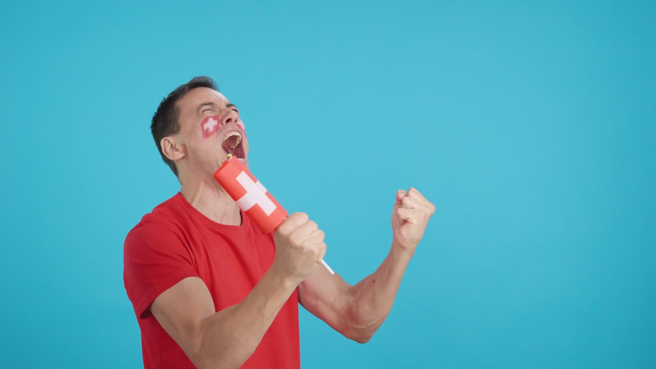 Man cheering for Switzerland waving a national flag looking away