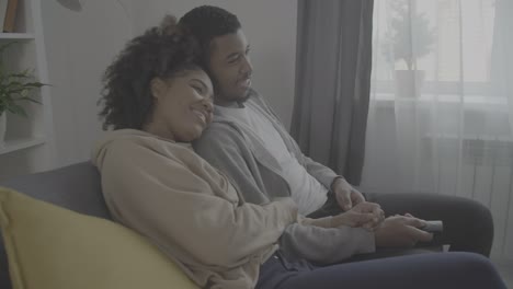 young african american couple laughing while watching a film