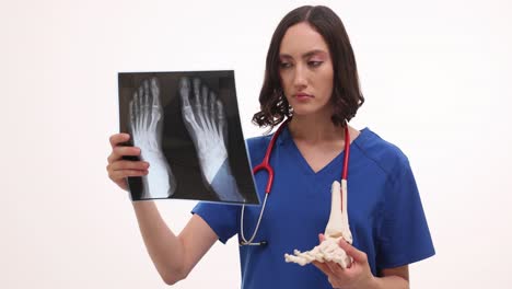 female doctor examining foot x-ray and skeleton model