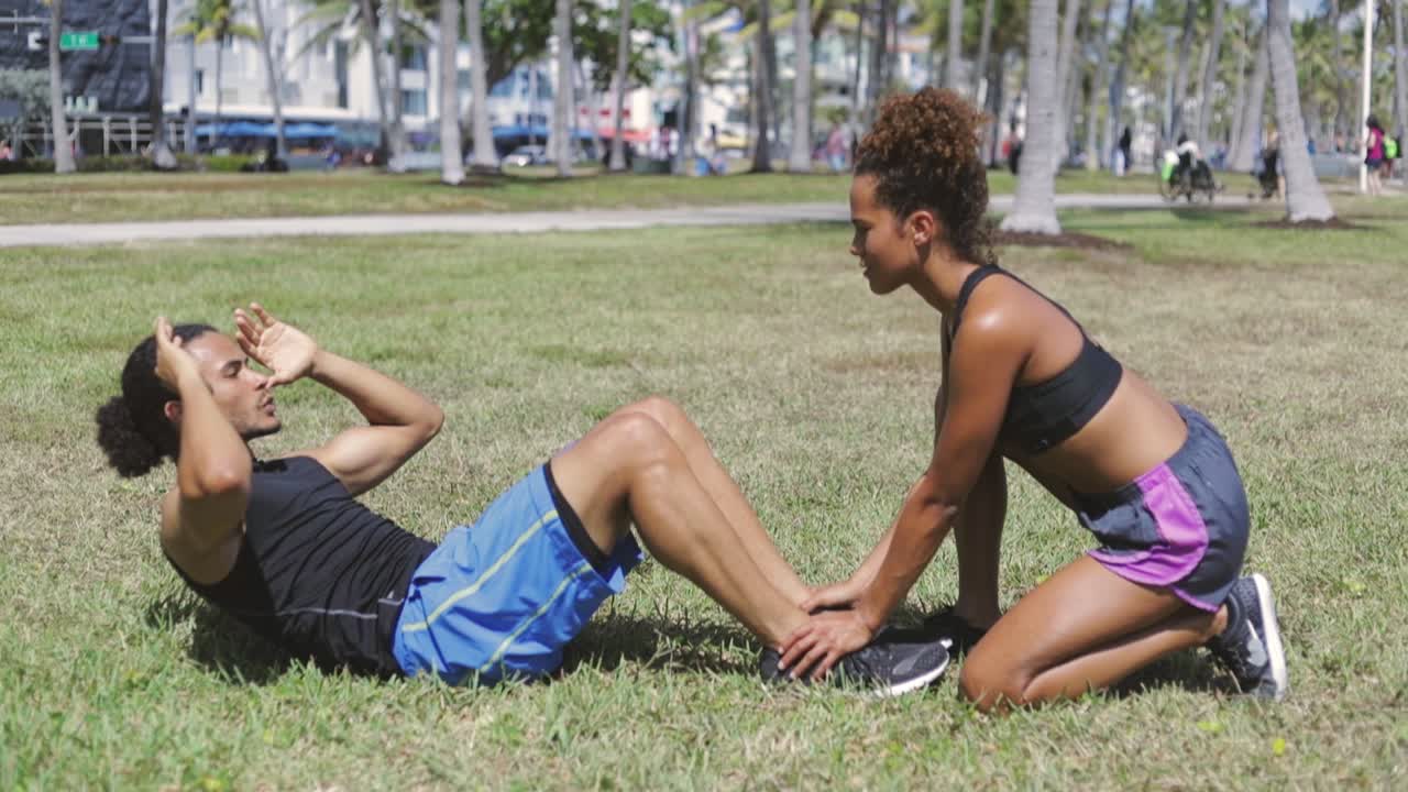 mujer ayudando a su novio con ejercicio abdominal