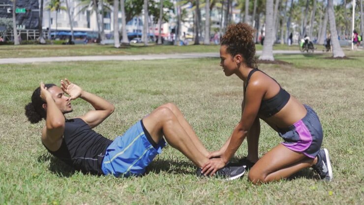 Woman helping to boyfriend with abdominal exercise