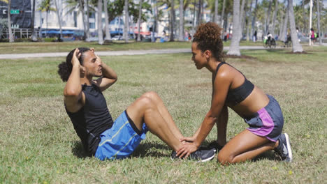 woman helping to boyfriend with abdominal exercise