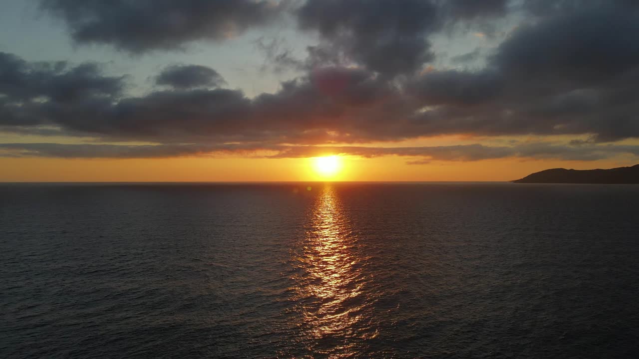 A beautiful, dramatic seascape sunrise over calm water. Stunning cloudscape ocean horizon.