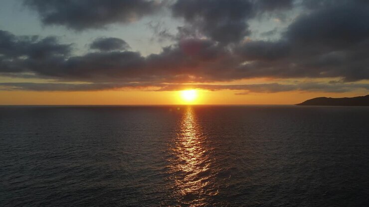 A beautiful, dramatic seascape sunrise over calm water. Stunning cloudscape ocean horizon.