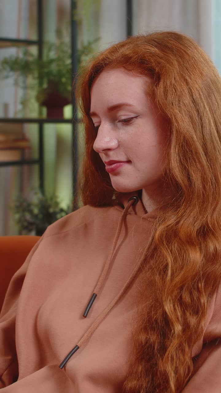 소파에 앉아있는 행복한 젊은 백인 여성은 카메라에 심장 기호를 보여주는 사랑의 상징을 만니다.