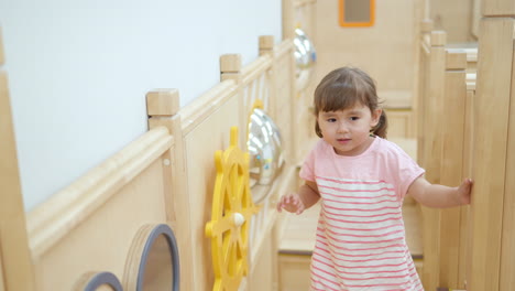 happy girl toddler playing in playroom, child turns steering wheel walking through baby obstacle course - tracking slow motion