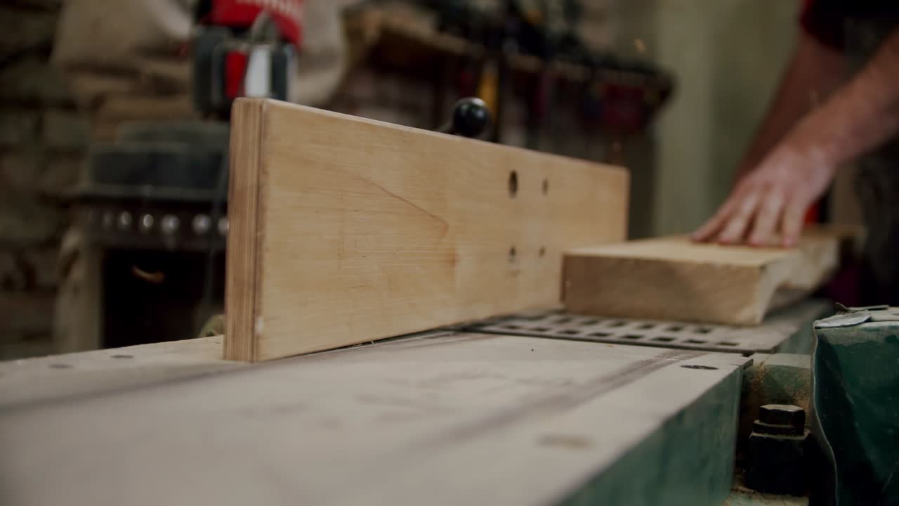 рабочий в деревообрабатывающей мастерской, берет доску и ставит ее на машину в деревообработывающей мастерской небольшого производителя мебели. v2
