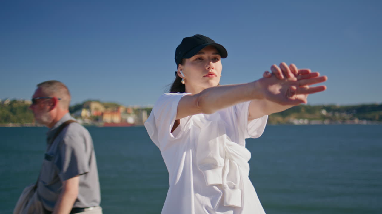 Girl athlete stretching arms at coast closeup. Serious woman fitness