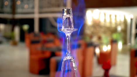 Close-tilt-up-along-Flaming-Lamborghini-cocktail-at-bar,-shallow-DOF