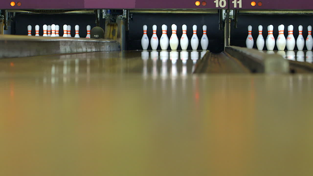 Stavěč kuželek staví kuželky na bowlingové dráze, záběr z nízkého úhlu