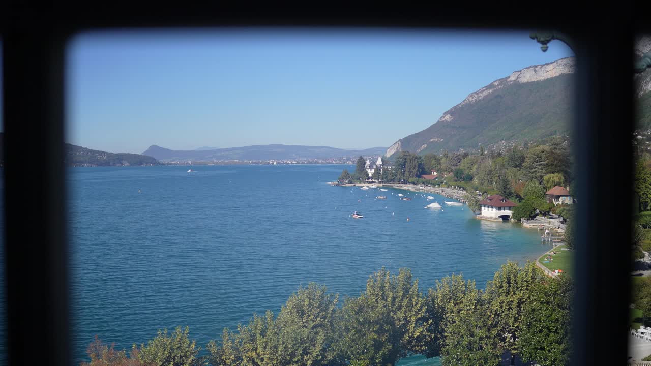 Lago di Annecy visto da una finestra a riquadri in una giornata di sole nelle Alpi francesi, ripresa panoramica a sinistra.