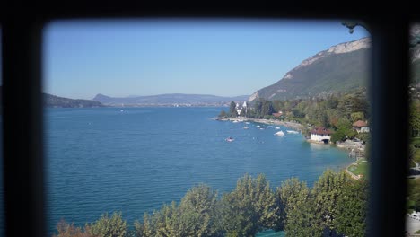 lake annecy seen from a tiled window on a sunny day in the french alps, pan left shot