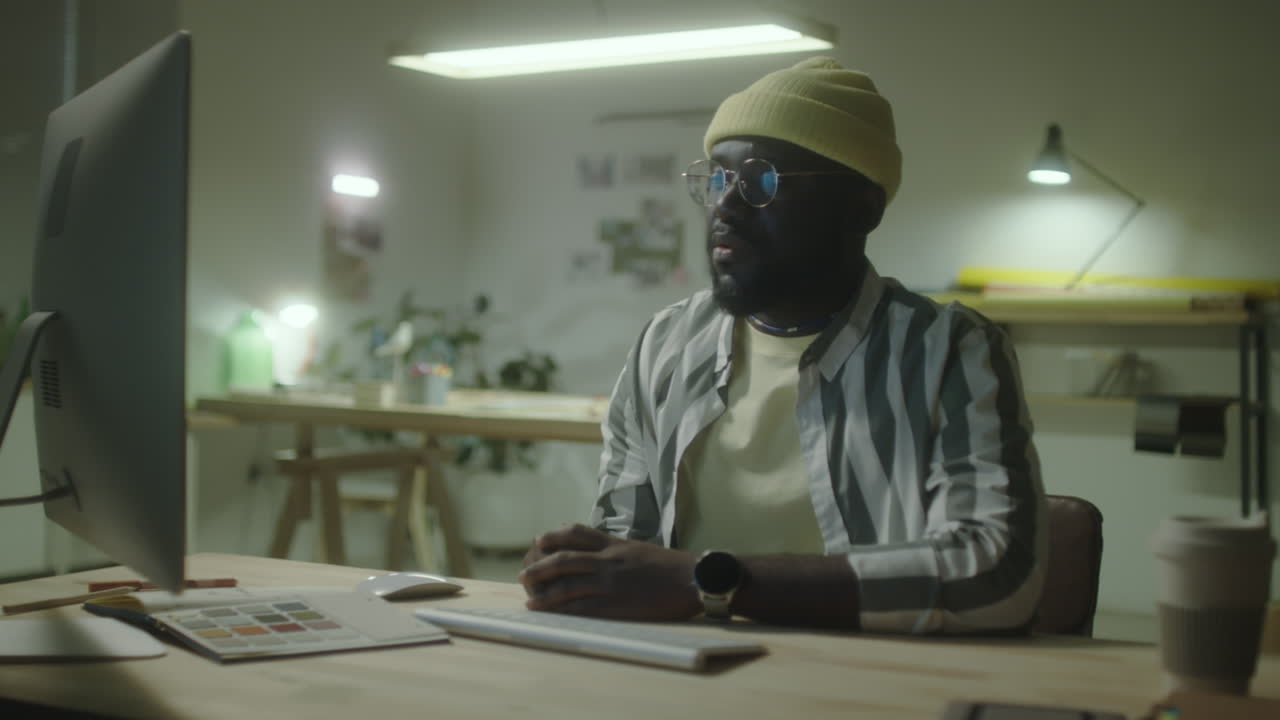 Uomo afroamericano che lavora al computer in un ufficio creativo.