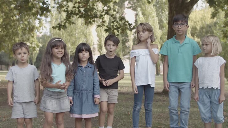 Bambini multietnici felici in fila che saltano nel parco