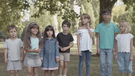 happy multiethnic children standing together in raw and jumping in the park