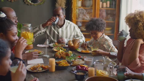 large family clinking glasses in toast at home dinner