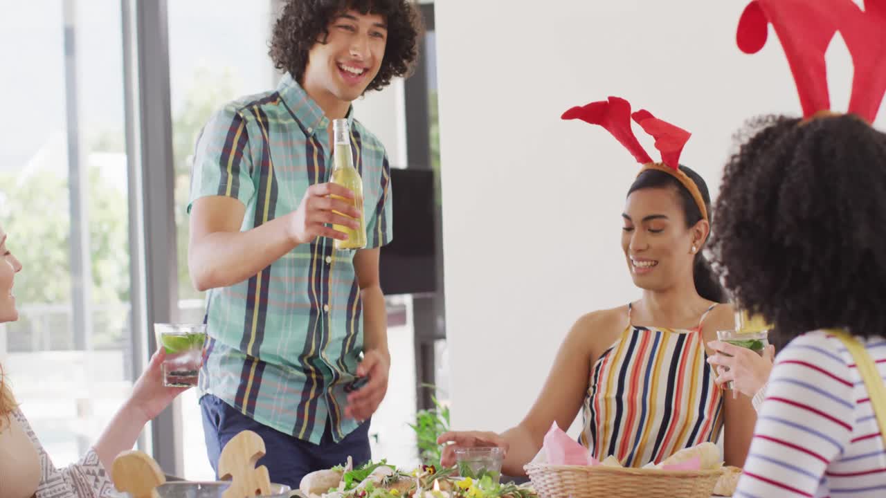 un grupo feliz de amigos diversos sentados a la mesa y cenando juntos, haciendo tostadas