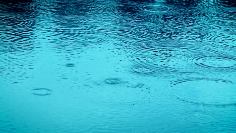 the blue color tone of close up rain water drop falling to the river surface in rainy season , 4k dci resolution