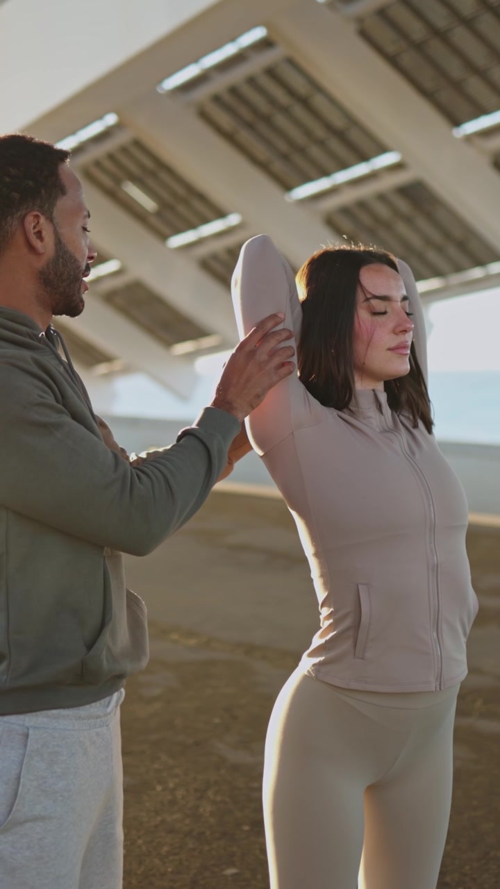 Personal trainer che assiste una donna con esercizi di stretching all'aperto